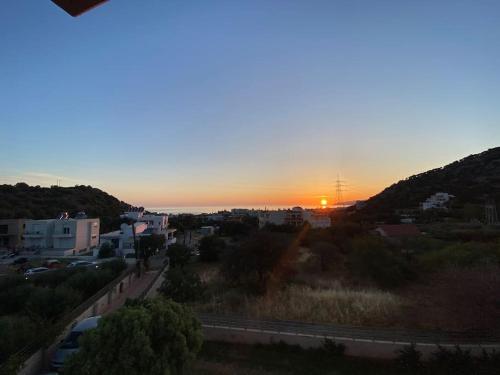 a sunset over a city with the sun setting at Astali Villa in Stalida
