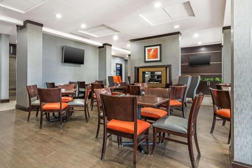 Best Western Plus Coweta's 1st Hotel في Coweta: غرفة طعام بها طاولات وكراسي وتلفزيون
