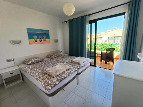 a bedroom with a bed and a view of a balcony at Castillo Mar - 82 in Caleta De Fuste