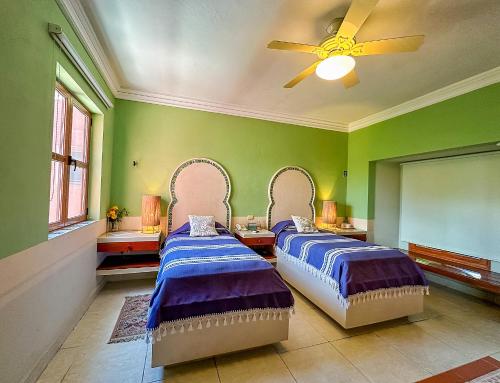 two beds in a room with green walls at Hotel Boutique Casa San Angel in Mérida