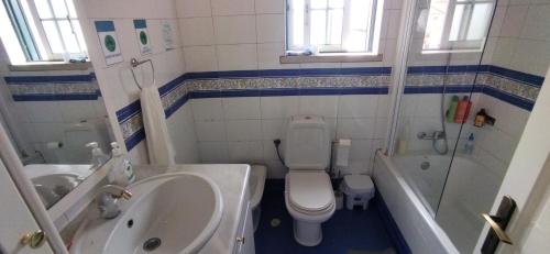 a bathroom with a toilet and a tub and a sink at Quarto privado 5 in Famões