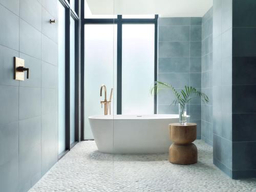 a bathroom with a tub and a potted plant at Kimpton - Grand Roatan Resort and Spa in West Bay