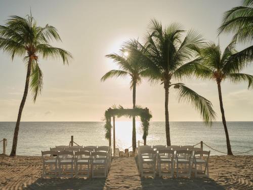 a table and chairs on the beach with palm trees at Kimpton - Grand Roatan Resort and Spa in West Bay