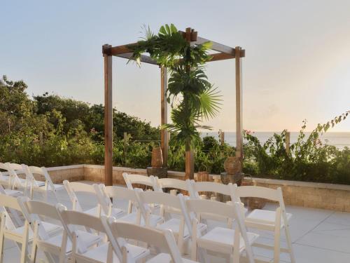 a group of white chairs are lined up at a table at Kimpton - Grand Roatan Resort and Spa in West Bay