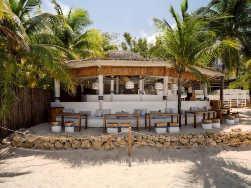 a resort on the beach with chairs and palm trees at Kimpton - Grand Roatan Resort and Spa in West Bay