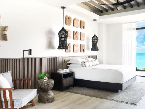 a bedroom with a bed and a chair and a window at Kimpton - Grand Roatan Resort and Spa in West Bay