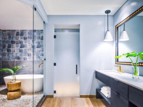 a bathroom with a tub and a glass shower door at Kimpton - Grand Roatan Resort and Spa in West Bay