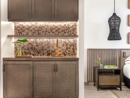 a kitchen with brown cabinets and a tiled wall at Kimpton - Grand Roatan Resort and Spa in West Bay