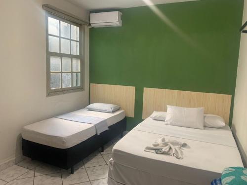 2 camas en una habitación con una pared verde en Bálsamo Hotel Marília, en Marília