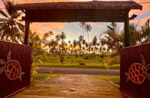 a gate to a road with palm trees in the background at Turtle Bay Beach House in Saraotou
