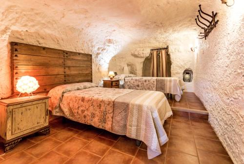 a bedroom with two beds and a wooden wall at Las Cuevas Del Abismo in Alcalá del Júcar