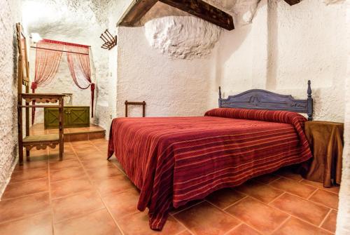 a bedroom with a bed with a red blanket at Las Cuevas Del Abismo in Alcalá del Júcar
