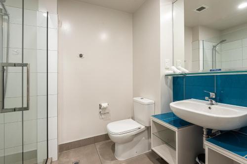 a bathroom with a white toilet and a sink at Quality Hotel Oceans Tutukaka in Tutukaka