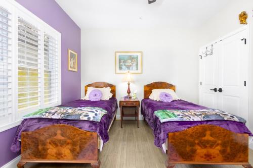 two beds in a room with purple and white walls at Deep Creek Retreat Hot Tub 85 inchTV all one level in Accident