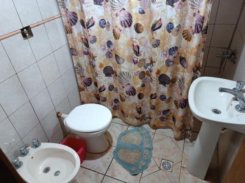 a bathroom with a toilet and a sink and a shower curtain at Apart la hermosa in Puerto Iguazú