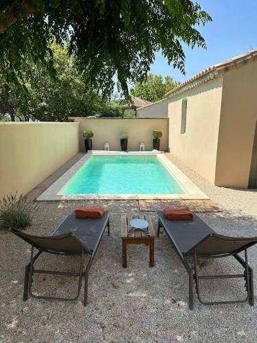 une piscine avec deux chaises et une table dans l'établissement Logement Cairanne, à Cairanne