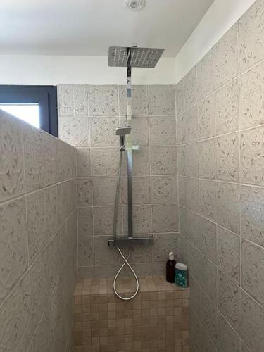 La salle de bains carrelée est pourvue d'une douche avec un pommeau de douche. dans l'établissement Logement Cairanne, à Cairanne