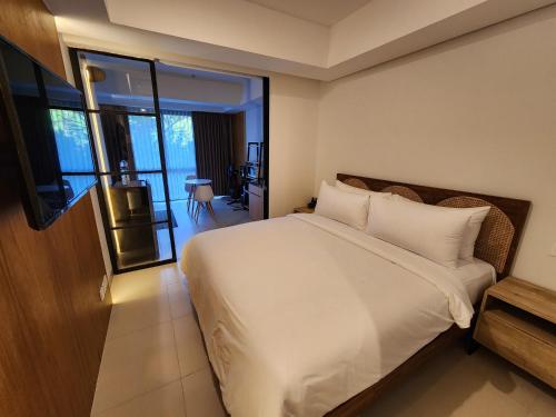 een slaapkamer met een wit bed en een balkon bij de' Asasta Apartment Benoa E216 in Nusa Dua