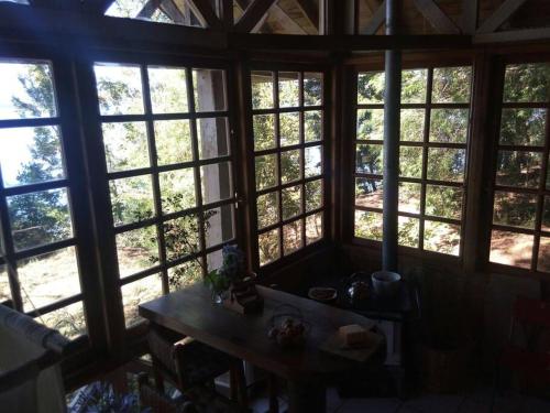a room with large windows with a table in front of it at House on Calafquen lake in Panguipulli