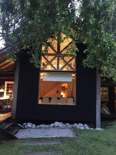 a black house with a window on the side of it at House on Calafquen lake in Panguipulli
