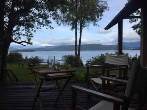 a table and chairs on a deck with a view of the water at House on Calafquen lake in Panguipulli