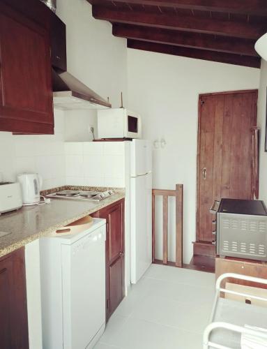 a kitchen with white appliances and a wooden door at Coutada dos Pinheiros - Pinheiros Farm House in Fafe