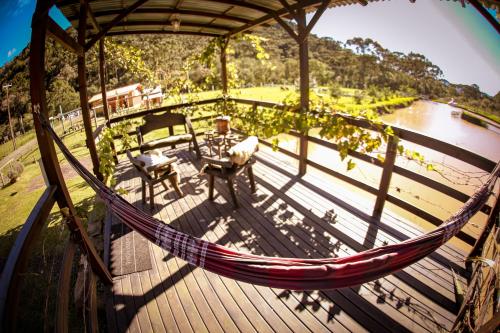 a hammock on a deck with a view of a lake at Pousada Nó de Pinho in Urubici