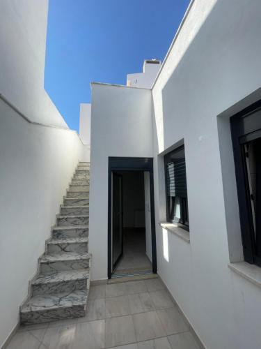una scala che conduce a un edificio bianco di PENICHE As Estrelas Proches centre ville et petite plage Trois établissements indépendants climatisés et de tout confort a Peniche