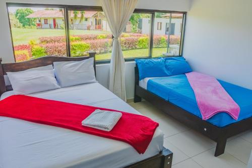 two beds in a room with a window at Finca Casa Blanca in Armenia