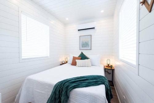 a white bedroom with a bed and two windows at The Stardust Stunning Container Home in Alpine