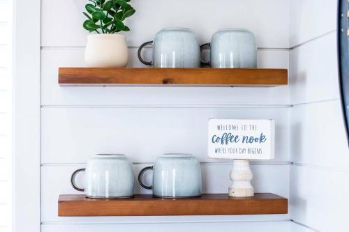 a shelf with coffee mugs and a sign on it at The Stardust Stunning Container Home in Alpine