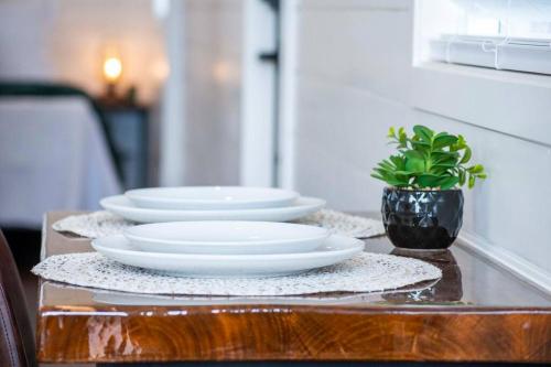 three white plates on a table with a potted plant at The Stardust Stunning Container Home in Alpine