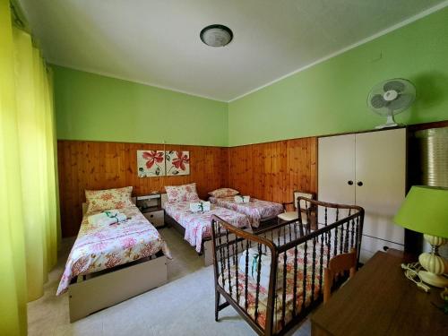 a bedroom with two beds and a crib in it at Da "Zia Giovanna" in San Giovanni Suèrgiu