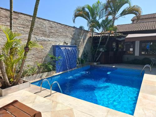 a swimming pool in front of a house with palm trees at Pousada Doce Paraty in Paraty