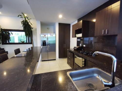 a kitchen with a sink and a stainless steel refrigerator at Casa condominio santa ana in Flandes