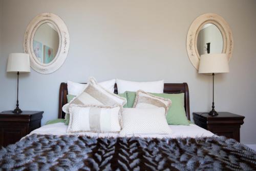 a bedroom with a bed with pillows and two mirrors at Apartment 88 in Greytown
