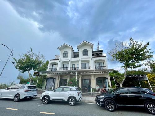 two cars parked in front of a white house at Huy Hoàng Hotel in Xóm Cầu Hin
