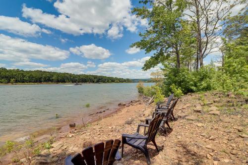 a row of chairs sitting on the shore of a river at Peaceful Greers Ferry Cabin with Deck and Lake View! in Fairfield Bay