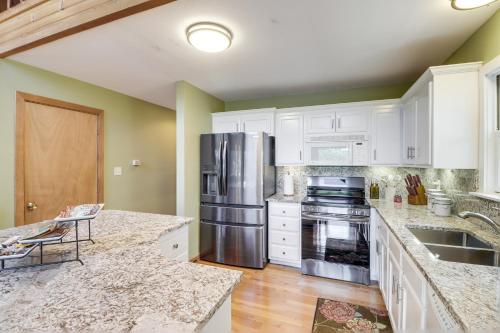 a kitchen with white cabinets and a stainless steel refrigerator at Peaceful Greers Ferry Cabin with Deck and Lake View! in Fairfield Bay