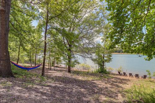 a hammock in the woods next to a lake at Peaceful Greers Ferry Cabin with Deck and Lake View! in Fairfield Bay