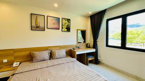 a bedroom with a bed and a desk and a window at Huy Hoàng Hotel in Xóm Cầu Hin