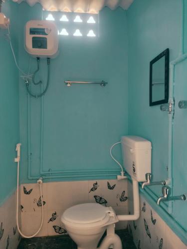a bathroom with a toilet and a blue wall at Boomerang community in Auroville