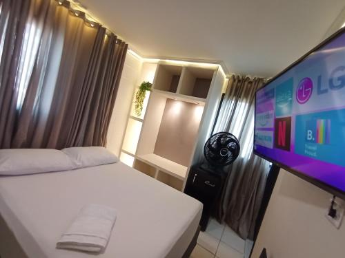 a bedroom with a bed and a flat screen tv at Praia do Bessa, Caribessa - Quarto Privativo - Conforto, Paz e Sossego, excelente para descansar, trabalhar ou estudar in João Pessoa