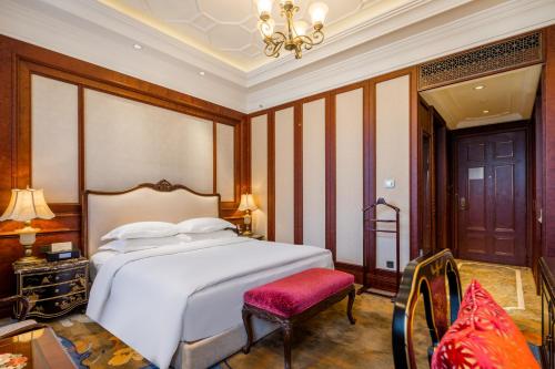 a bedroom with a white bed and a red chair at Shanghai Donghu Hotel - Shanghai Style Garden House in Shanghai