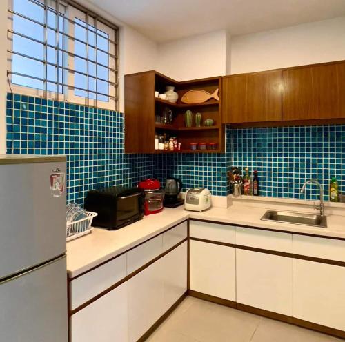 ブンタウにあるCăn Hộ View Biển - Thuy Tien Apartmentの青いタイルの壁、白いキャビネット付きのキッチン