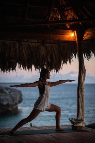 a woman in a white dress doing yoga on the beach at Bo'a Vida Rote in Nembrala