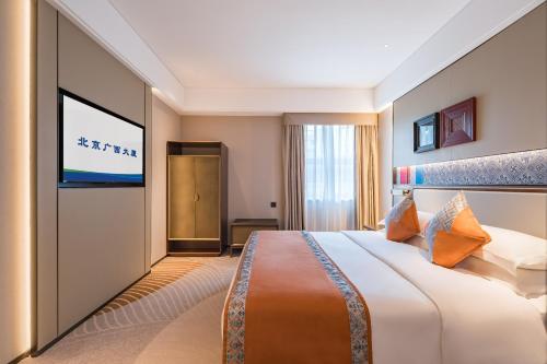 a hotel room with a bed and a flat screen tv at Beijing Guangxi Hotel in Beijing