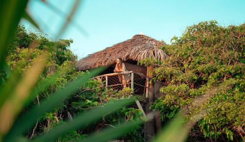 a person sitting on a balcony of a thatch hut at Bo'a Vida Rote in Nembrala