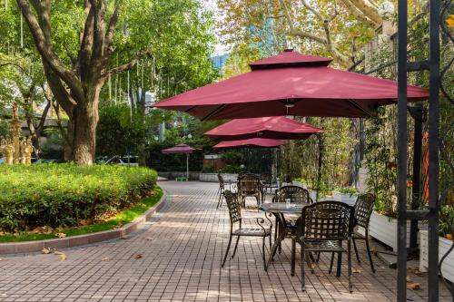 a table and chairs under a red umbrella at Shanghai Donghu Hotel - Shanghai Style Garden House in Shanghai