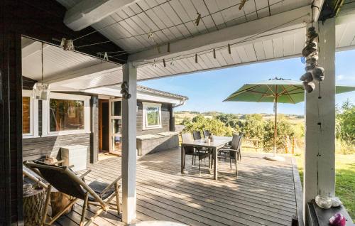 a wooden deck with a table and an umbrella at Holiday Home Tværvangen in Ebeltoft
